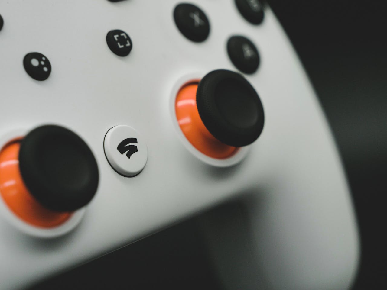 Detailed close-up of a modern white gaming controller featuring vibrant orange buttons.